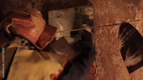 A scarier clown with knife at crude basement with a mirror on the wall