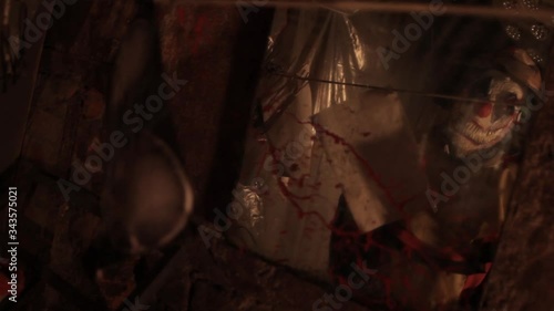 A scarier clown with knife at crude basement with a mirror on the wall