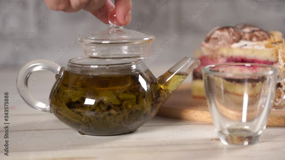 Close up of green tea in teapot and cup on white wooden table. Close up of green tea in teapot and cup on white wooden table.