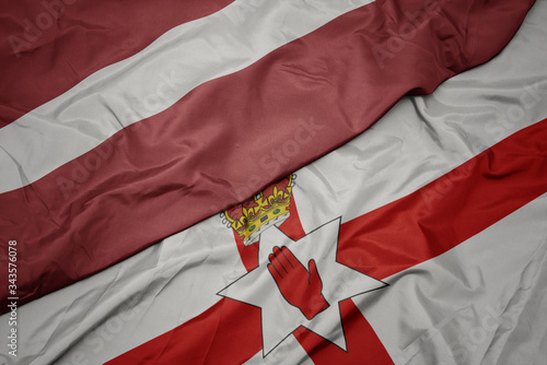 waving colorful flag of northern ireland and national flag of latvia.