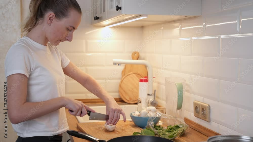 A woman prepares dinner. Cuts mushrooms with a knife A woman prepares dinner. Cuts mushrooms with a knife