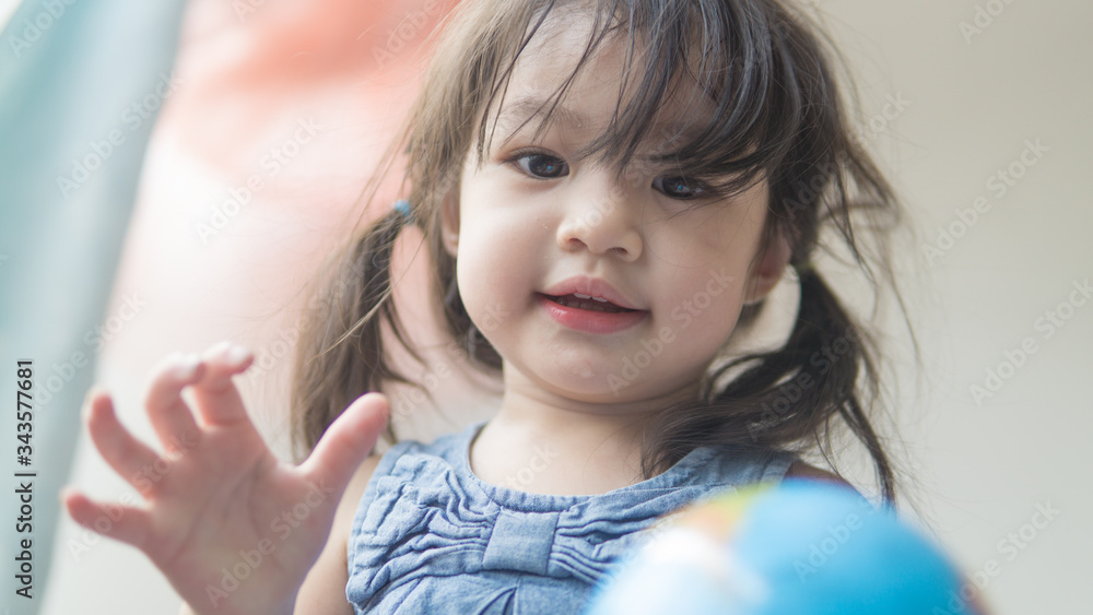 Happy playful toddler looking at globe ball on bed in bedroom at home. Happy playful toddler looking at globe ball on bed in bedroom at home.
