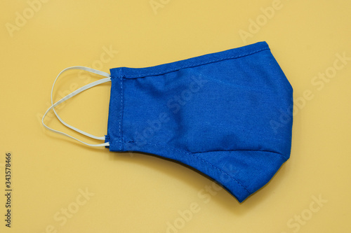 blue fabric mask surgical filter dust pollution and disease corona virus or covid -19 . safety medical equipment. Isolated on yellow background.