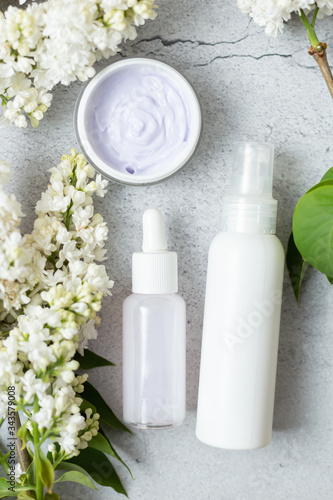 Flat lay composition with white bottles. Mockup for organic natural products. Aromatic organic cosmetic products made from lilac flowers. Skin care concept.