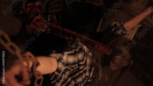 Silhouette of man maniac or killer or horror murderer with chainsaw in hand in dark creepy and spooky room. Criminal robber or rapist concept in thriller atmosphere with  victim girl