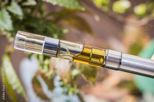 a vape pen with golden cannabis extracted oil filled cartridge. Isolated up-close