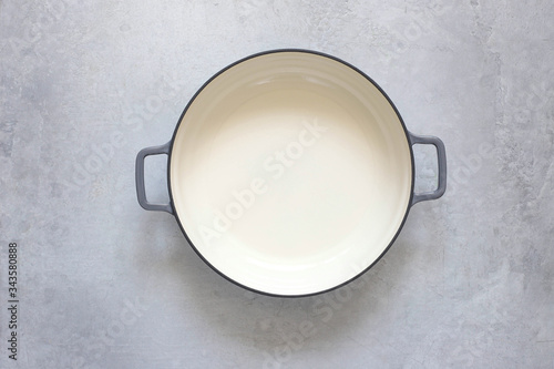 фотографія An empty cast-iron pot on a gray concrete background.