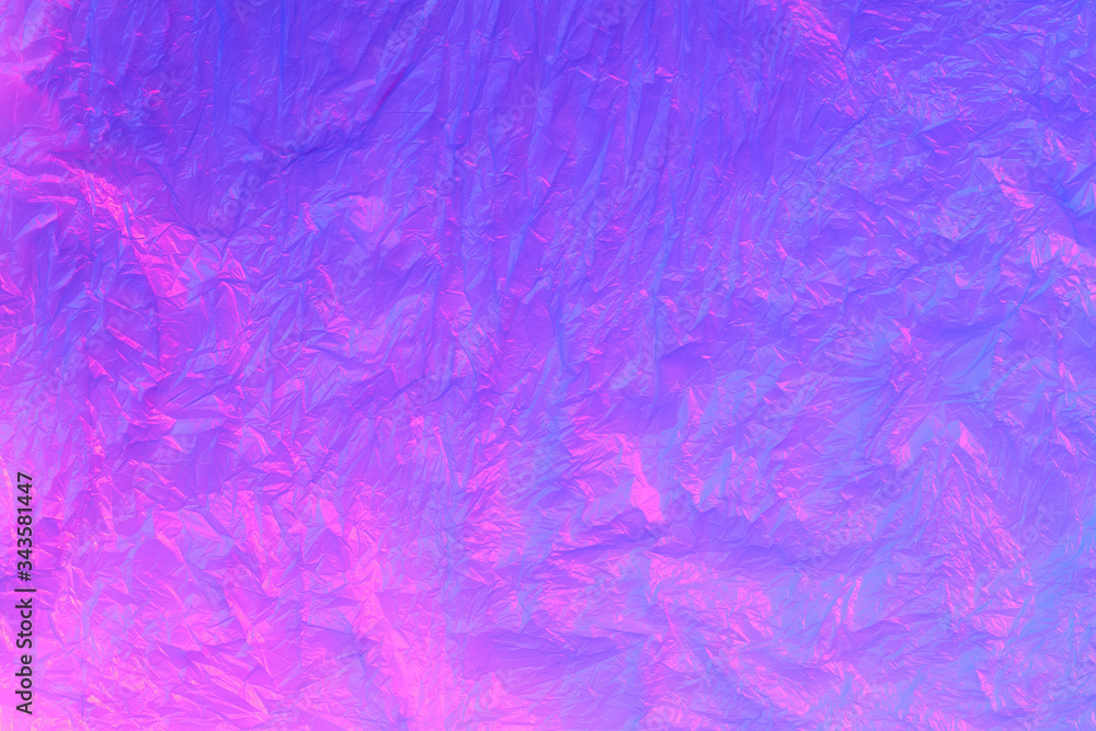 Background from purple recyclable polyethylene in neon pink light. Eco, zero waste, alternative to plastic concept. Flat lay. Horizontal. Closeup