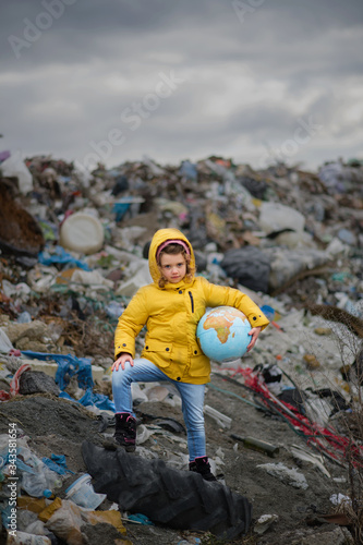 Small child holding globe on landfill, environmental pollution concept.