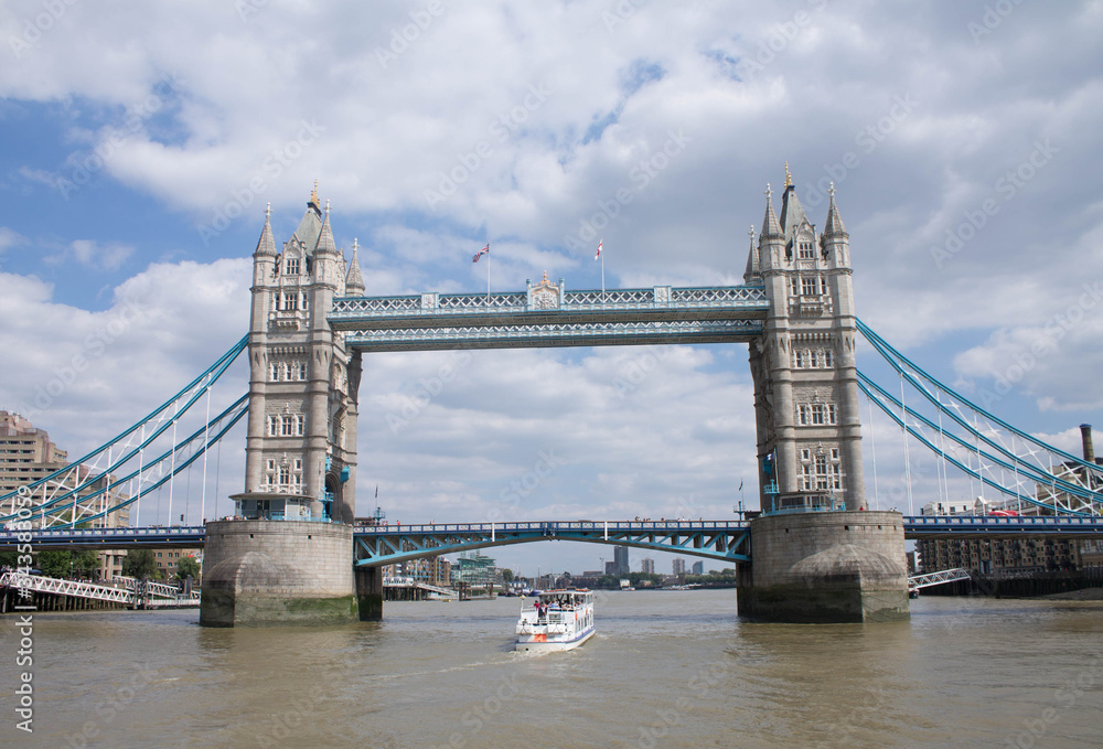Panoramic of the London Bridge with tourist boat crossing from below this, London UK.
