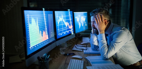 Photos Frustrated businessman with computer sitting at desk, working late