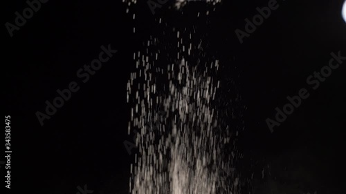 baker's hand sifting flour on black background