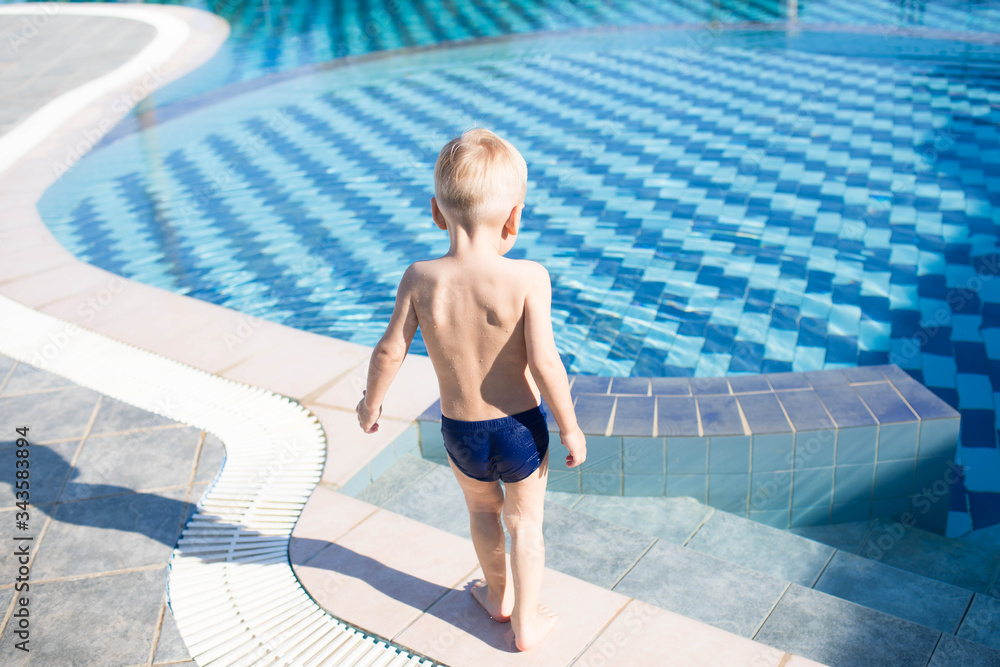 A little boy goes swimming in the pool on a Sunny summer day. A little boy goes swimming in the pool on a Sunny summer day.