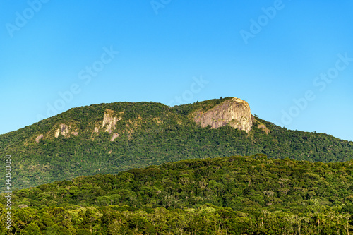 large white stone hill surrounded by green rainforest under a blue sky
