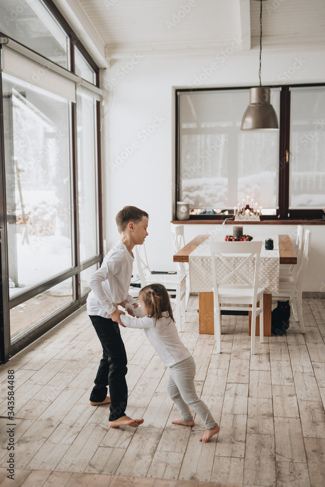 Family in a big house. Lifestyle Home comfort. Children at home. Beautiful kitchen. Brother and sister play in the kitchen. Windows to the floor. Huge windows. Family in a big house. Lifestyle Home comfort. Children at home. Beautiful kitchen. Brother and sister play in the kitchen. Windows to the floor. Huge windows.