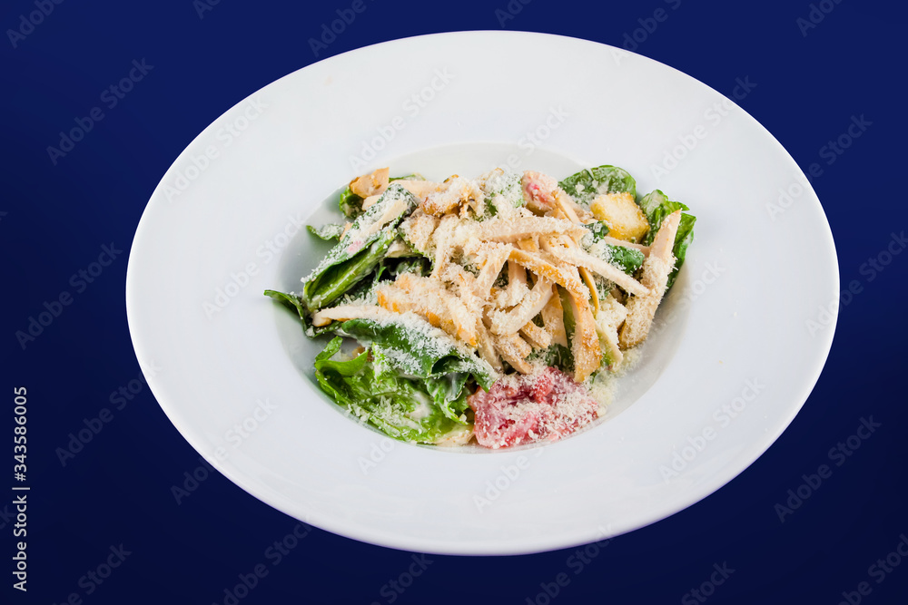 Plate with fresh caesar salad. Closeup on a white plate on a blue background. Plate with fresh caesar salad. Closeup on a white plate on a blue background.