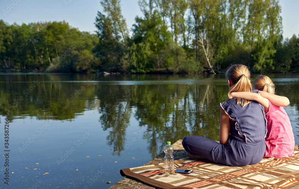 Freundinnen für ein Leben lang, sitzen am See umarmen sich und genießen die Zweisamkeit. Freundinnen für ein Leben lang, sitzen am See umarmen sich und genießen die Zweisamkeit.