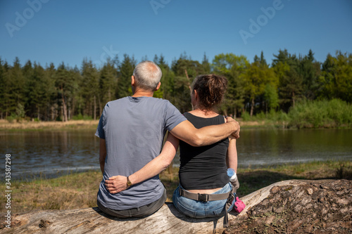 Couple sitting side by side and embracing at a lake