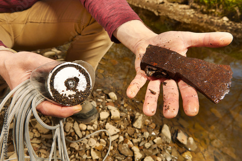 Man found rusty iron metal axe in river water by magnet photo