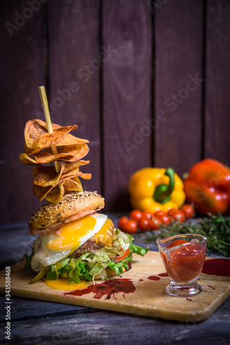 juicy beef burger with egg and potato chips salad on the background of wooden boards 