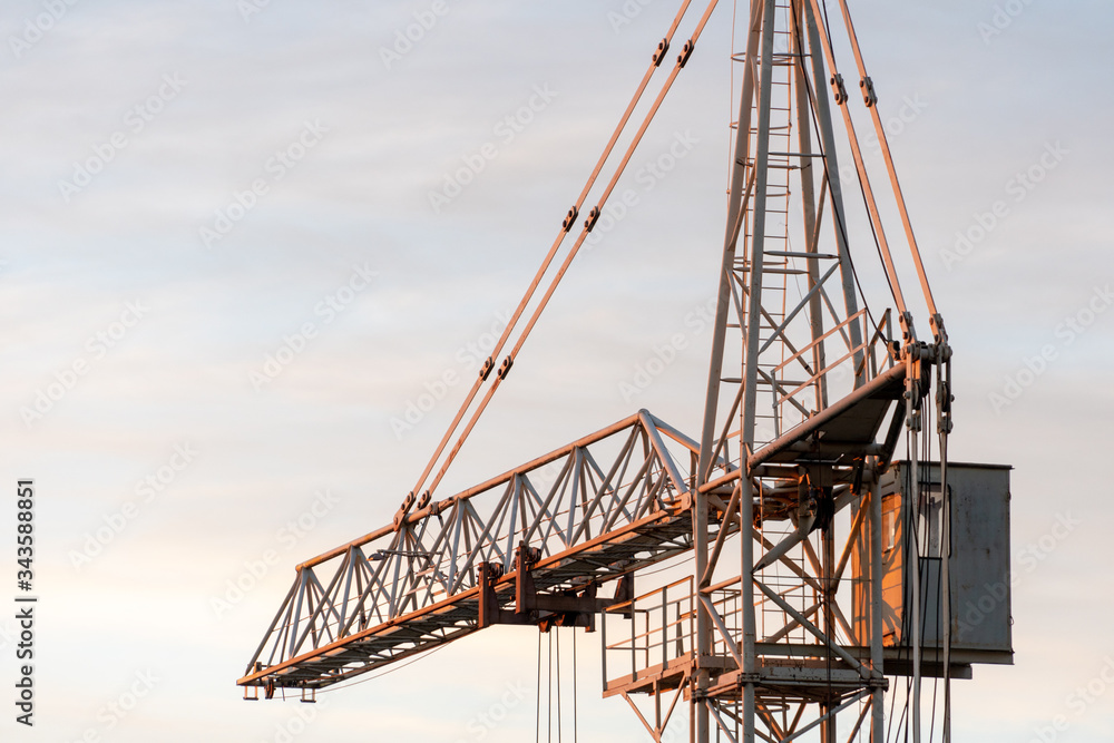 tower crane on the background of the sky at sunset. The boom of a construction crane closeup.