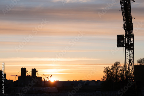 Evening outline of the city. The silhouette of the factory against the sky or sunset. The tower crane operates on the territory of the factory. photo