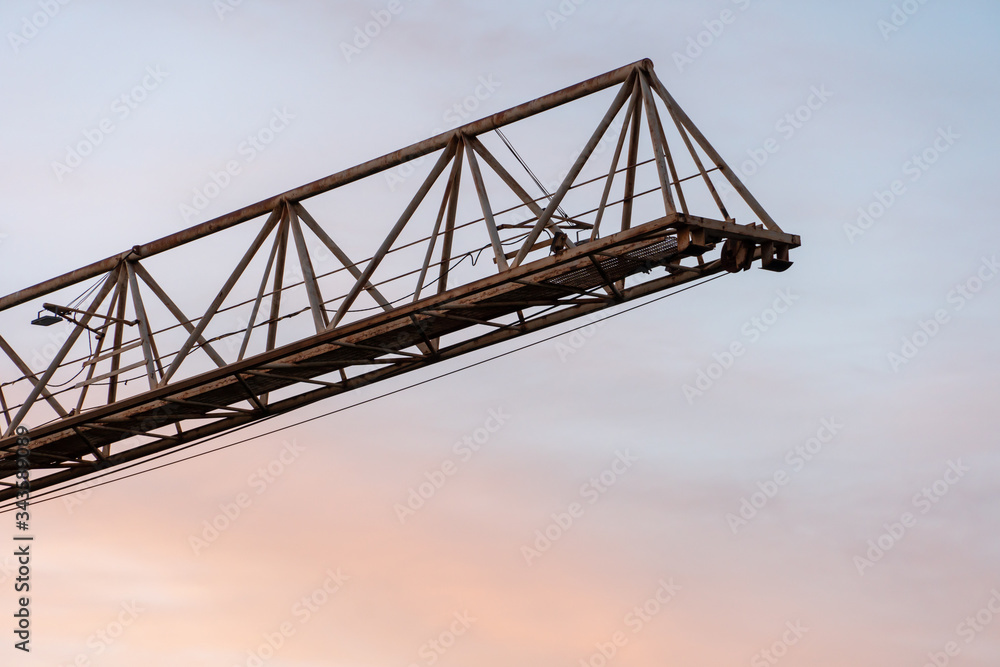 tower crane on the background of the sky at sunset. The boom of a construction crane closeup.