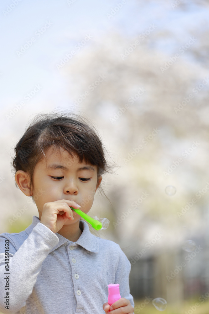 シャボン玉で遊ぶ幼児(5歳児)と青空