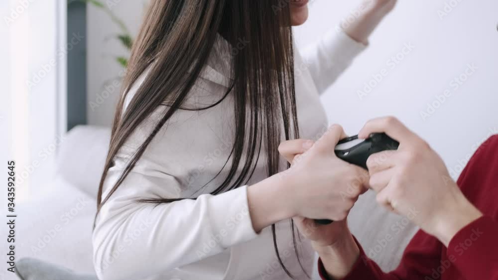 Beautiful young girl and boyfriend are playing video games. The couple is having fun together at home. This is an interesting idea of quarantine activity. Beautiful young girl and boyfriend are playing video games. The couple is having fun together at home. This is an interesting idea of quarantine activity.