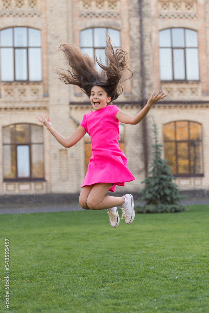 Girl jumping outdoors. Feel free. Jump of happiness. Small girl jump on green grass. Full of energy. Active girl feel freedom. Fun and relax. Carefree kid on summer holiday. Teen in pink dress