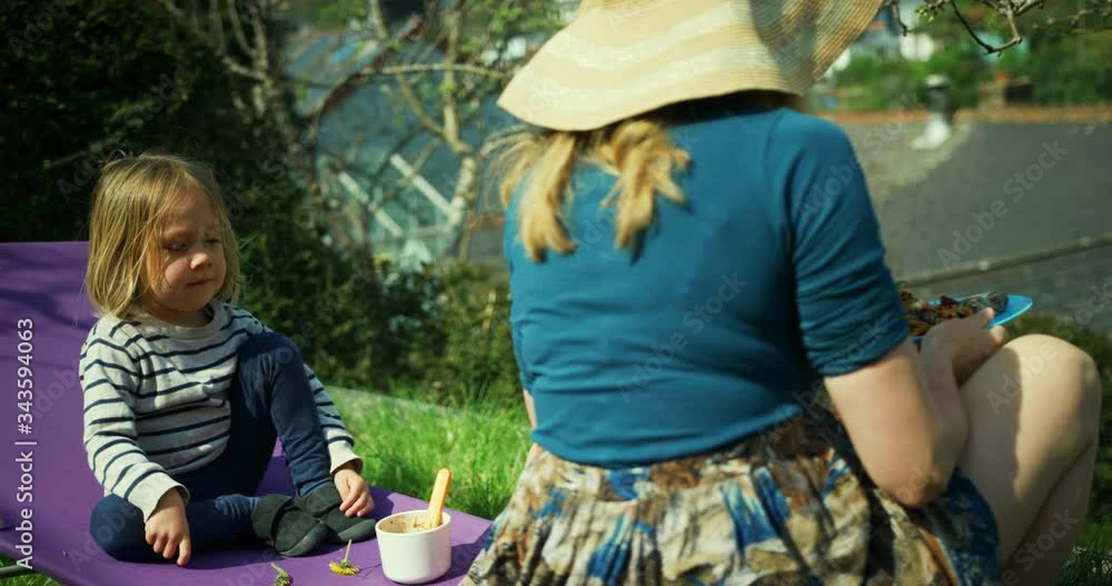 Mother and preschooler having lunch on sun lounger in garden Mother and preschooler having lunch on sun lounger in garden