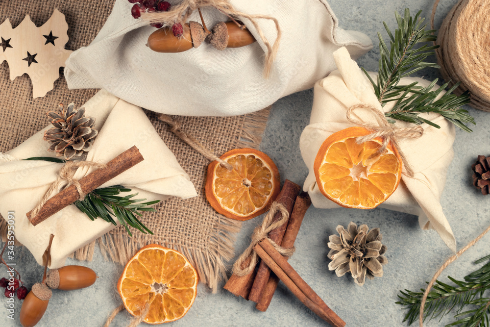 Obraz premium Zero waste christmas concept. Packed in natural fabric gifts and decorations from natural materials on gray table, top view
