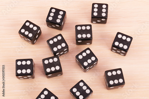 Black game dice showing the six on all face.Many cubes for board games on light background.Selective focus.Concept of victory, competition, luck in games.Top view.Close up.