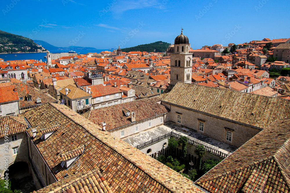 Aerial view of Dubrovnik and its Franciscan monastery in Croatia - Medieval old town on the coast of the Adriatic Sea with tile-roofed houses surrounded by defensive stone walls Aerial view of Dubrovnik and its Franciscan monastery in Croatia - Medieval old town on the coast of the Adriatic Sea with tile-roofed houses surrounded by defensive stone walls