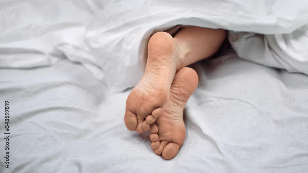 Close up bare female foot lying on comfortable bed under blanket. Shot on RED Raven 4k Cinema Camera Close up bare female foot lying on comfortable bed under blanket. Shot on RED Raven 4k Cinema Camera