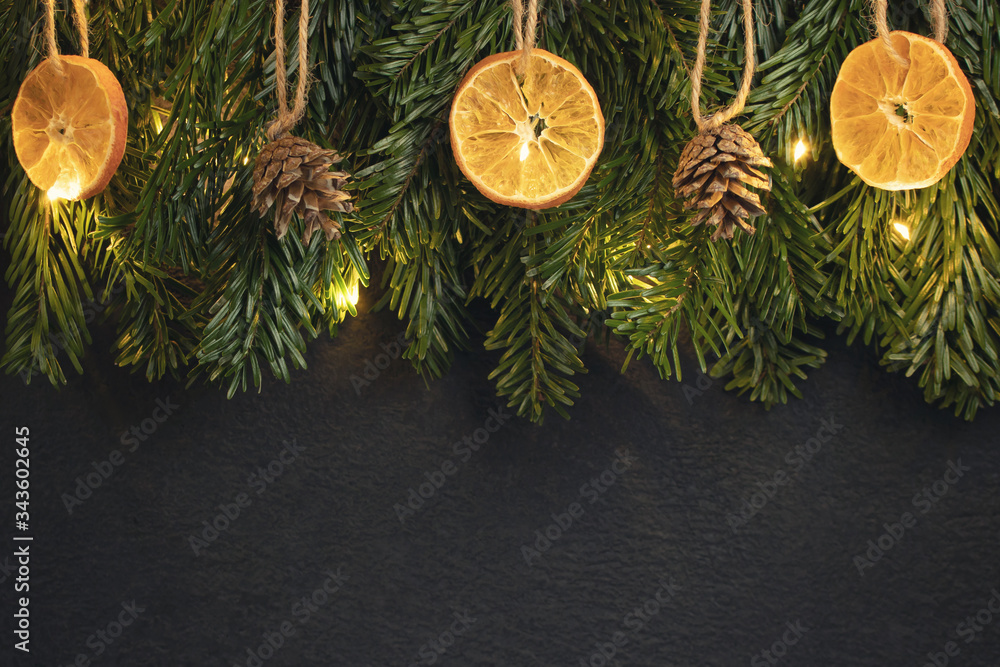 Zero waste and eco friendly christmas concept. Christmas tree branches with natural decorations on a black wall. Horizontal banner with copy space