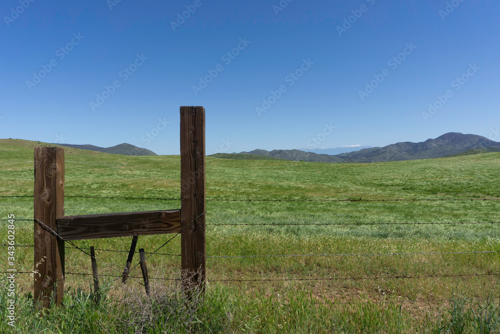 Countryside landscape with wood post barbed wire fence and a blue sky