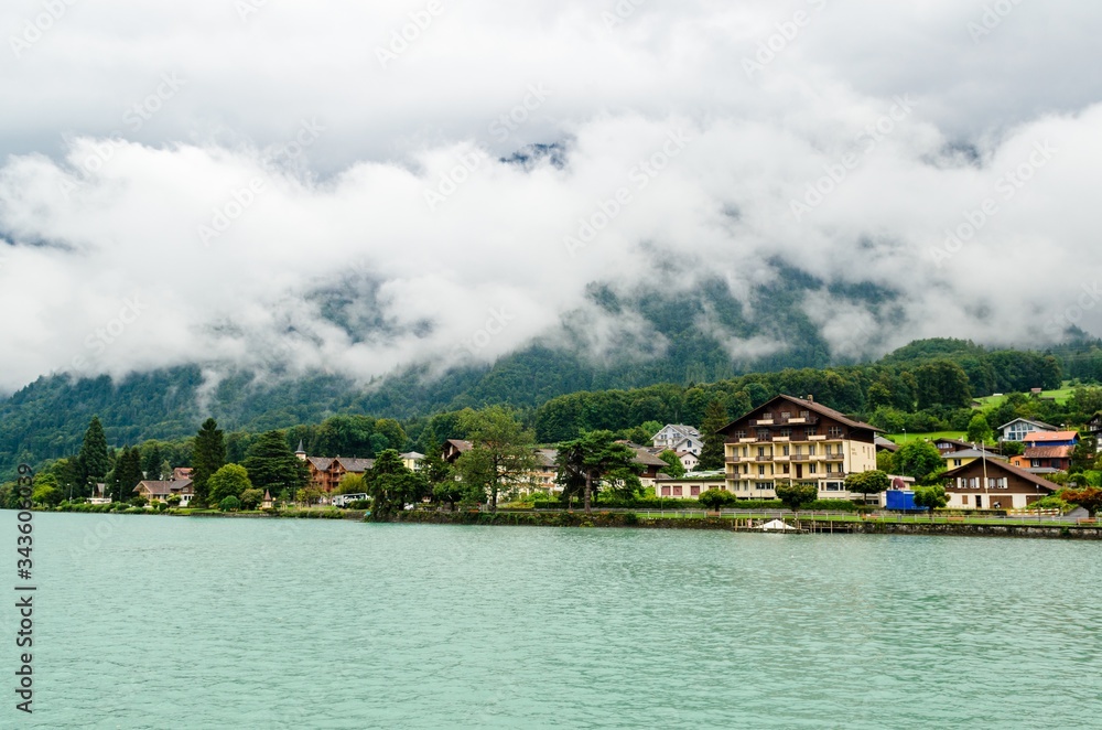 Brienzersee, lake of Brienz with cloudy alps mountains in clouds. Houses of Interlaken, Canton Bern, Switzerland
