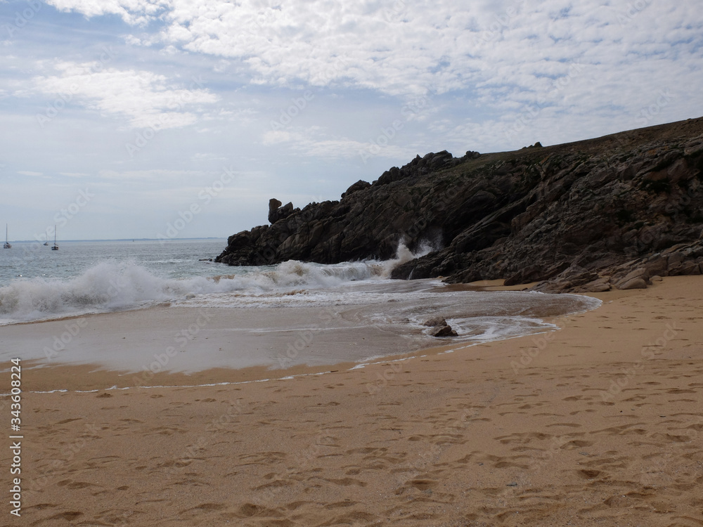 Une plage de sables fin avec la côte rocheuse surplombant la mer