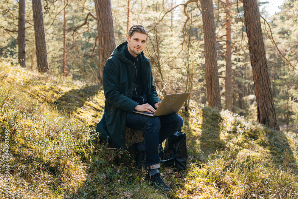 Man using a laptop work in forest. Young man sitting on an old tree strain work remotely in nature. Work everywhere traveler blogger outdoors. Businessman sitting in forest Remote working concept
Man using a laptop work in forest. Young man sitting on an old tree strain work remotely in nature. Work everywhere traveler blogger outdoors. Businessman sitting in forest Remote working concept