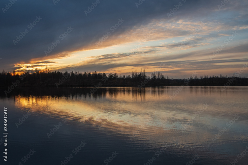 Colorful reflections of clouds in the water on sunset in pink and yellow, focus on foreground