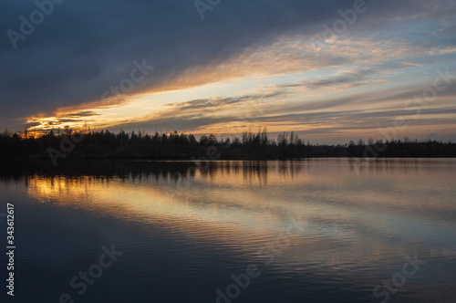 Colorful reflections of clouds in the water on sunset in pink and yellow, focus on foreground