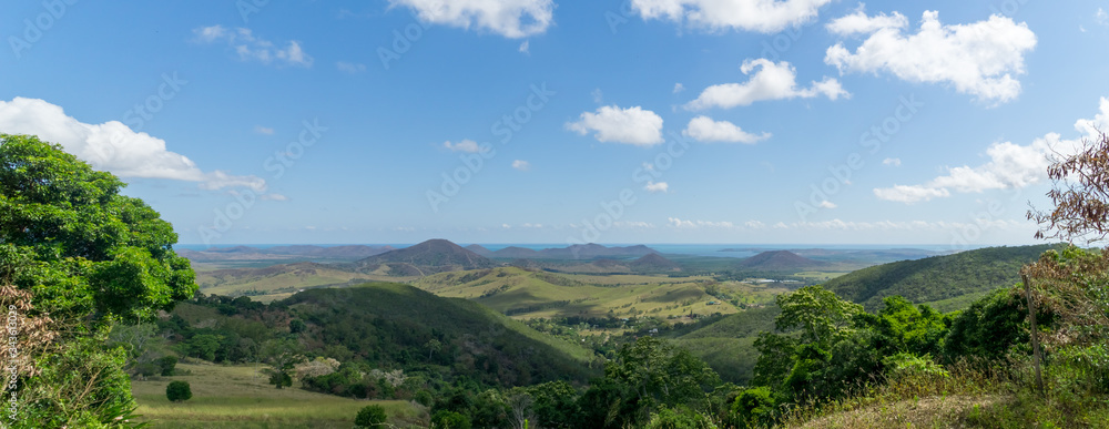 panorama of new Caledonia. sky is blue with white clouds. hill and sea in the background.