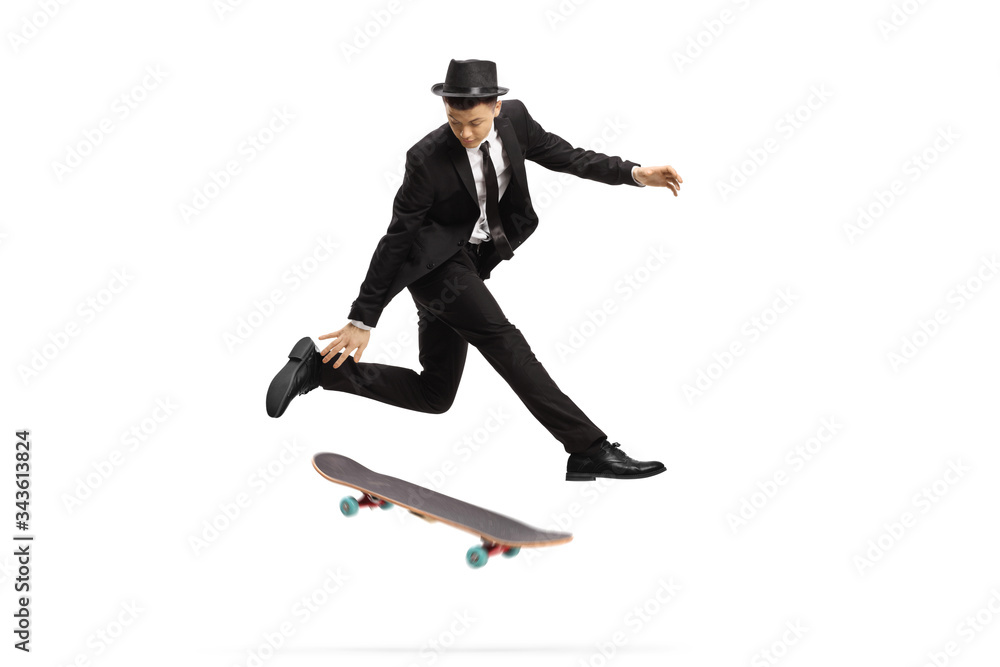 Young man in an elegant suit jumping with a skateboard
