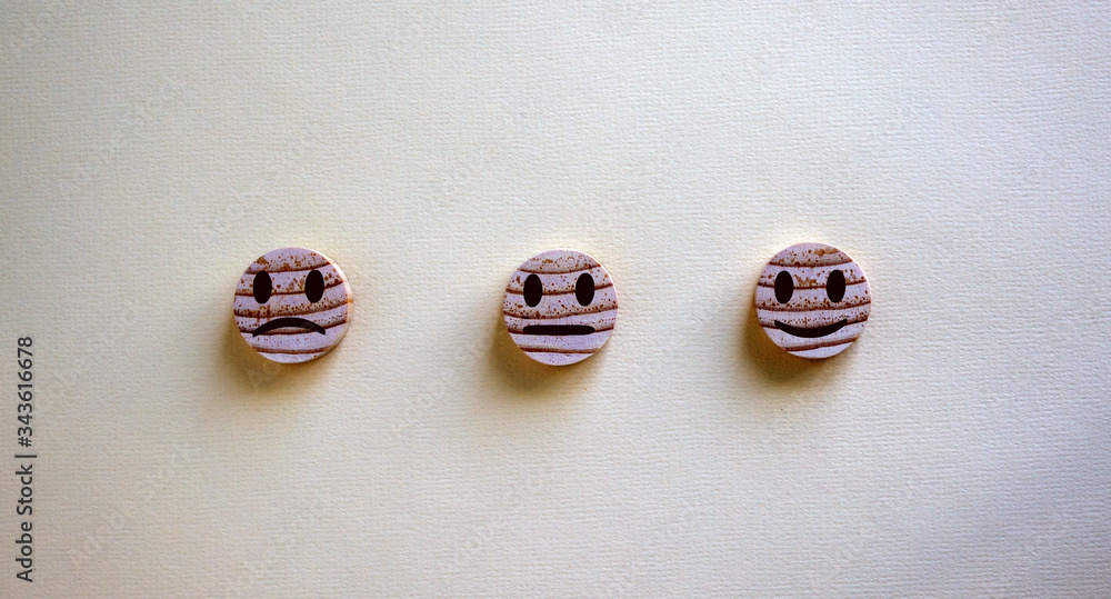 Various emoticons made of wooden circles and hand drawn lines of a mouth. Over yellow background in a conceptual image of quality and feedback. Various emoticons made of wooden circles and hand drawn lines of a mouth. Over yellow background in a conceptual image of quality and feedback.