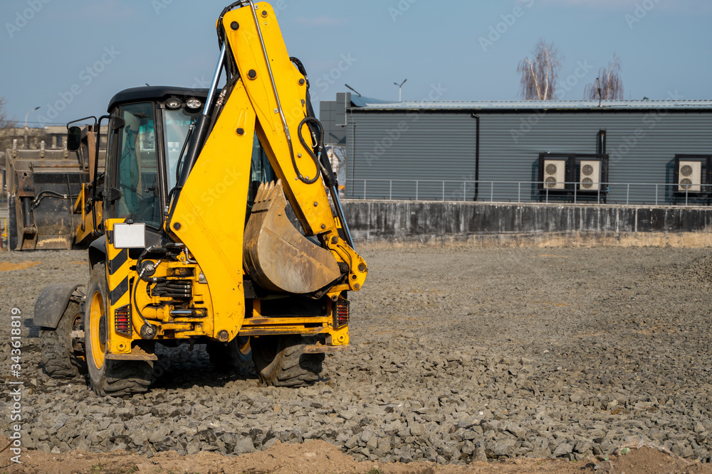 Obraz premium Yellow wheel loader Excavator machine working at construction site with a sand and gravel. Preparing of the fundament for a asphalting. Road construction site. Building of a parking.
