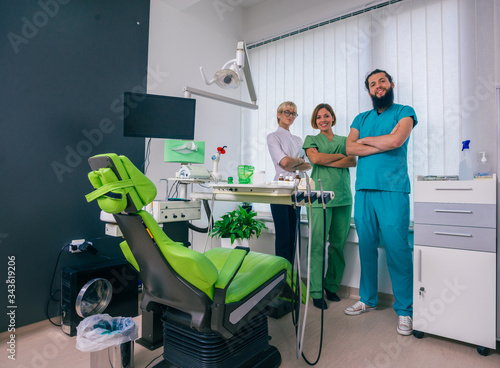Team of three happy dentists proudly posing in a dental office