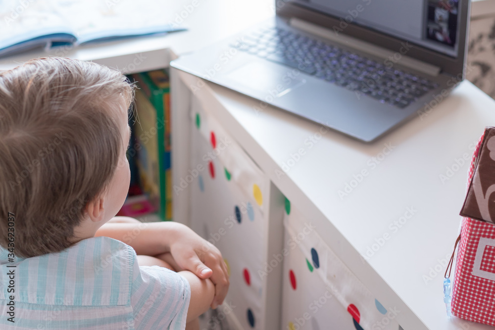 Cute european boy learns on-line at school the internet and laptop at home during quarantine. The concept of distance learning Cute european boy learns on-line at school the internet and laptop at home during quarantine. The concept of distance learning