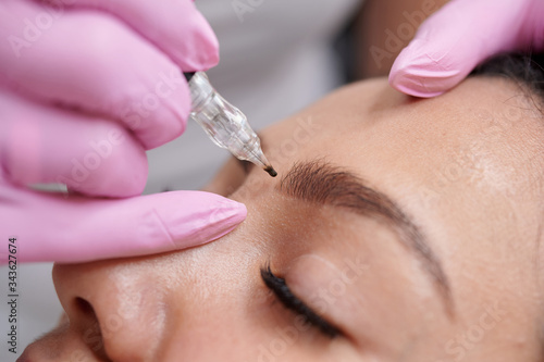 Female getting permanent eyeliner tattoos enhancement coloring in spa