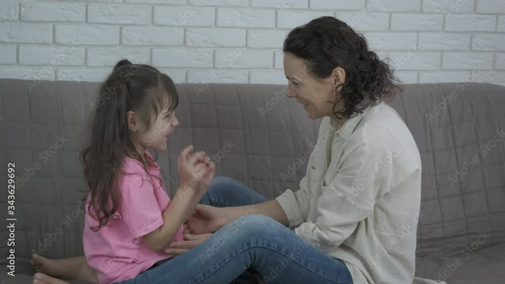Entertainment with mother on sofa. Cheerful little girl having fun with her mother at home. Entertainment with mother on sofa. Cheerful little girl having fun with her mother at home.